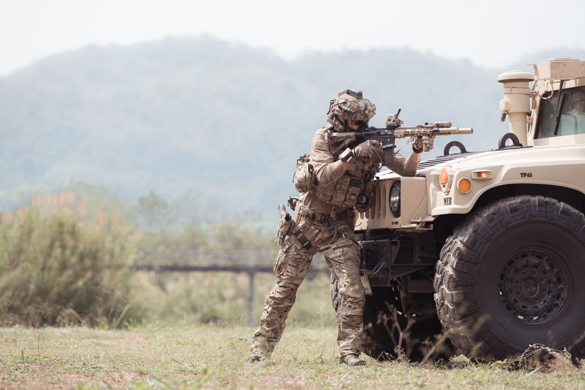 Soldiers in camouflage uniforms hold weapons ready to fire, By hiding on the side military communication vehicle